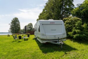 kamper postawiony przy drzewach, obok czarne leżaki