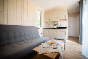 jasno-brązowy aneks kuchenny, szara sofa i stolik kawowy